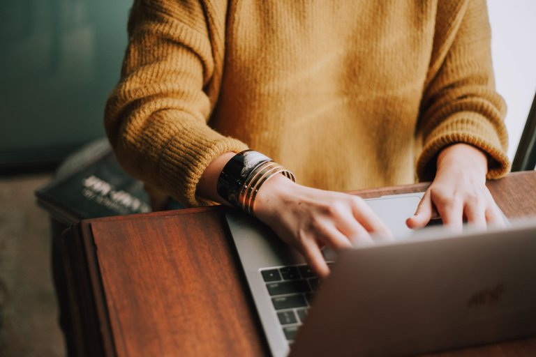 Bilde: Person i gul genser som skriver på en datamaskin.