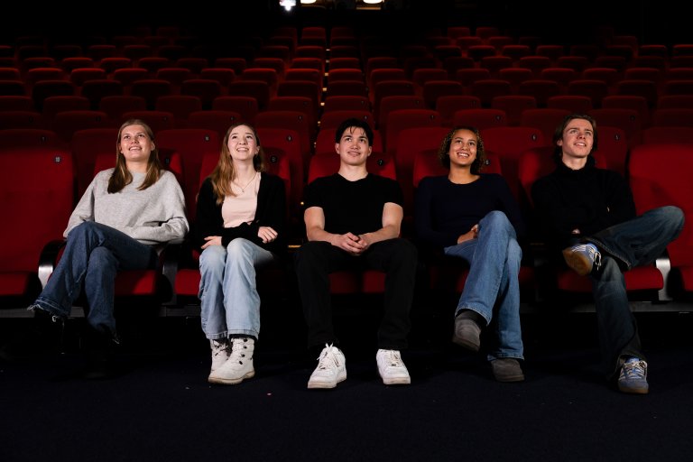 Fem ungdommer sitter i kinosal og ser på lerretet