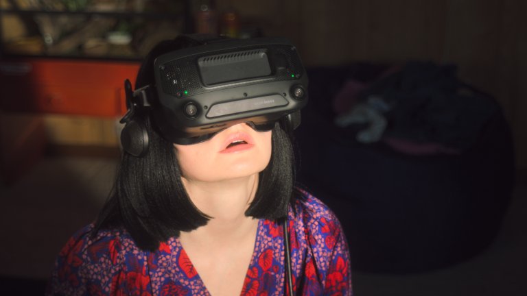 foto. kvinne i  halvfigur med virtuell virkelighet maske foran ansiktet