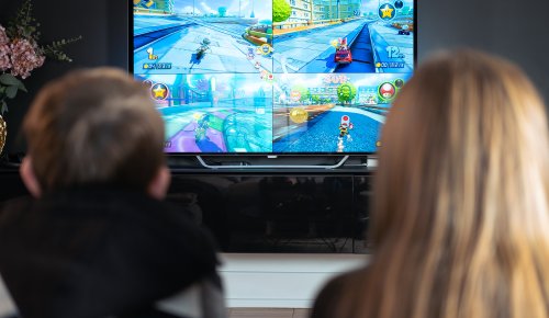 foto. bakhodet på to barn som sitter foran en tv og spiller bilspillet Mario Kart