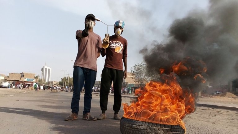 Foto.Two men in front of a burning tire